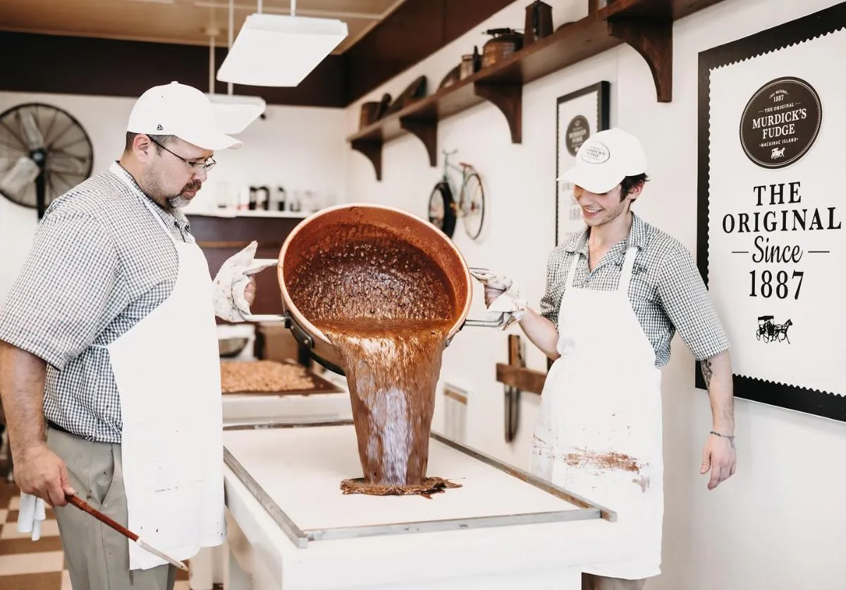 A confectioner artisan folding fudge on a traditional marble slab