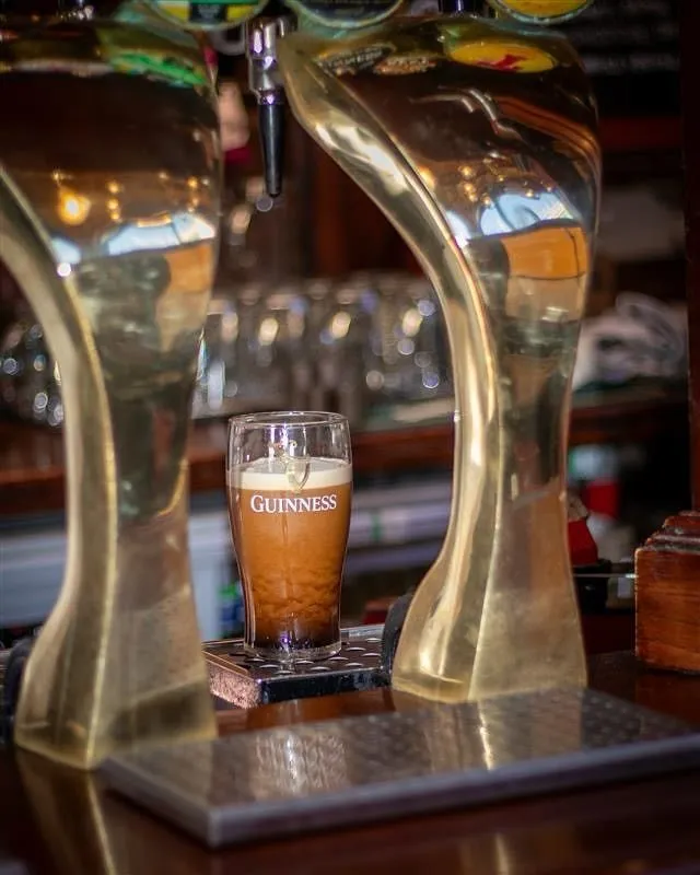 Pint of dark ale on a wooden table inside a pub