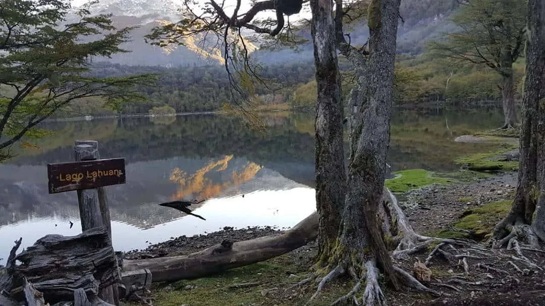 Rustic wooden mountain refuge beside a calm glacial lake in Patagonia