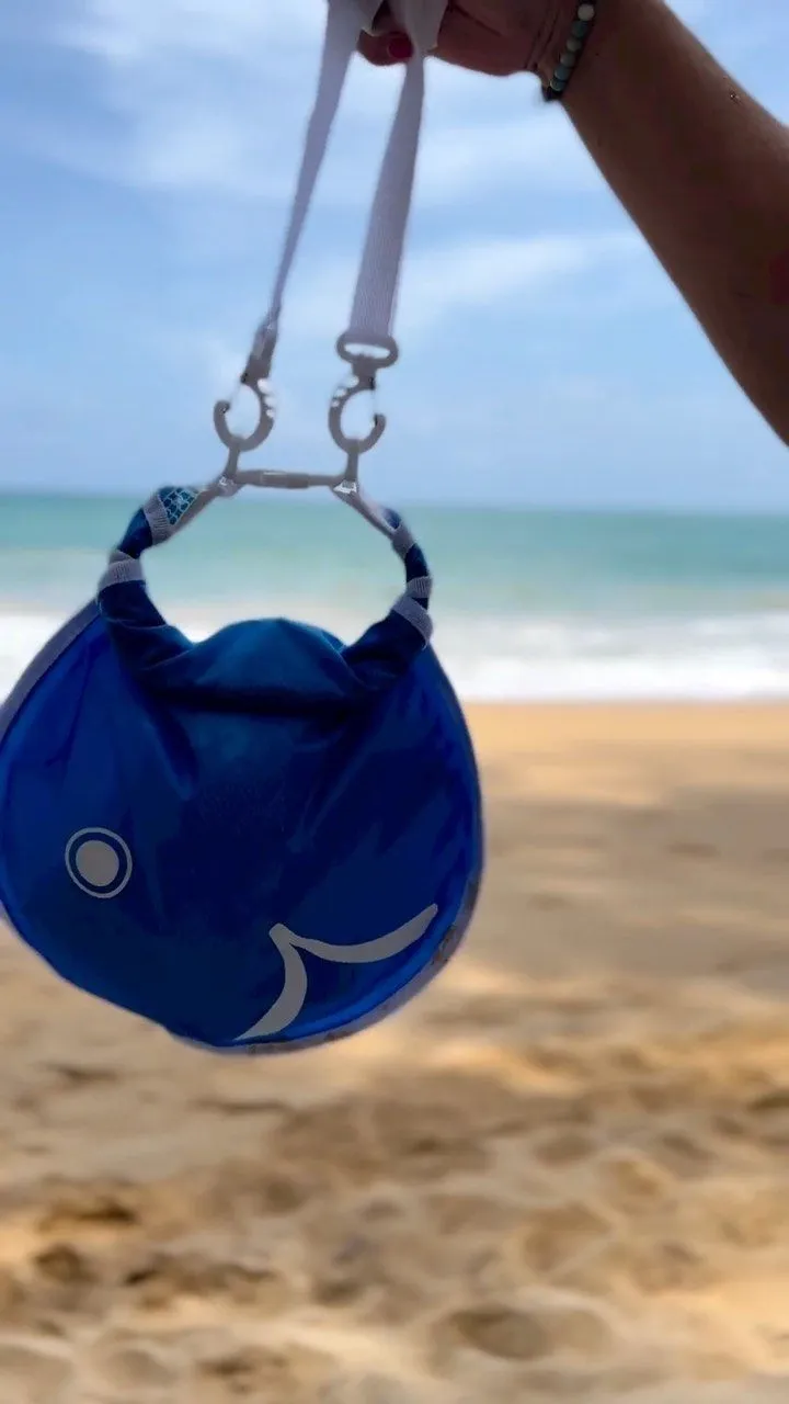 A traveler rolling down the top of an orange Wickelfisch dry bag by the river