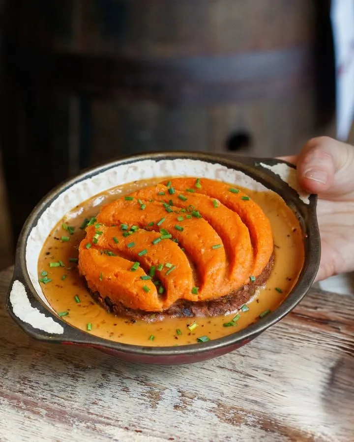 Steaming baked potato filled with vegetarian haggis on a wooden bench