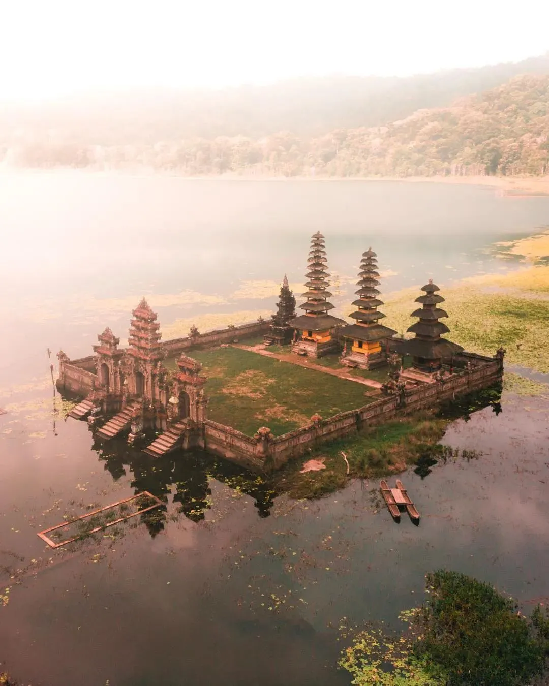 Ancient stone temple surrounded by forest at the edge of Lake Tamblingan