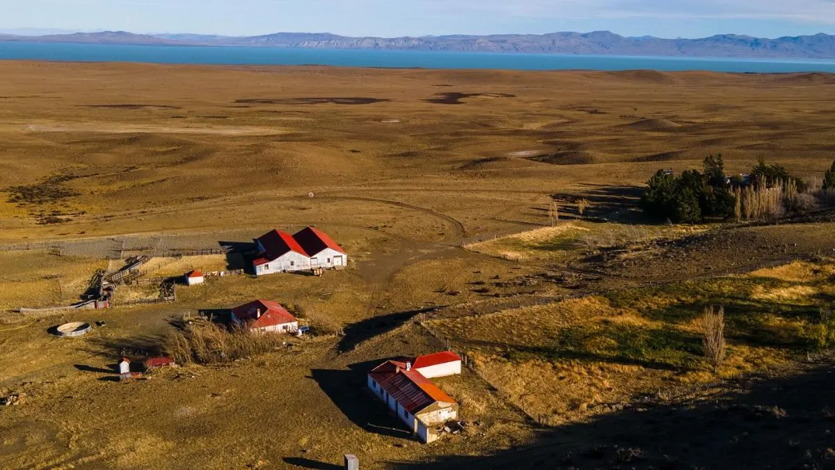 Historic buildings of Estancia Cristina sitting in a lush green valley surrounded by Patagonian mountains.