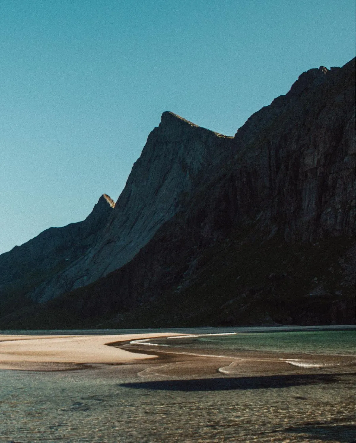 Towering green mountains surrounding the white sands of Horseid Beach in the Lofoten Islands