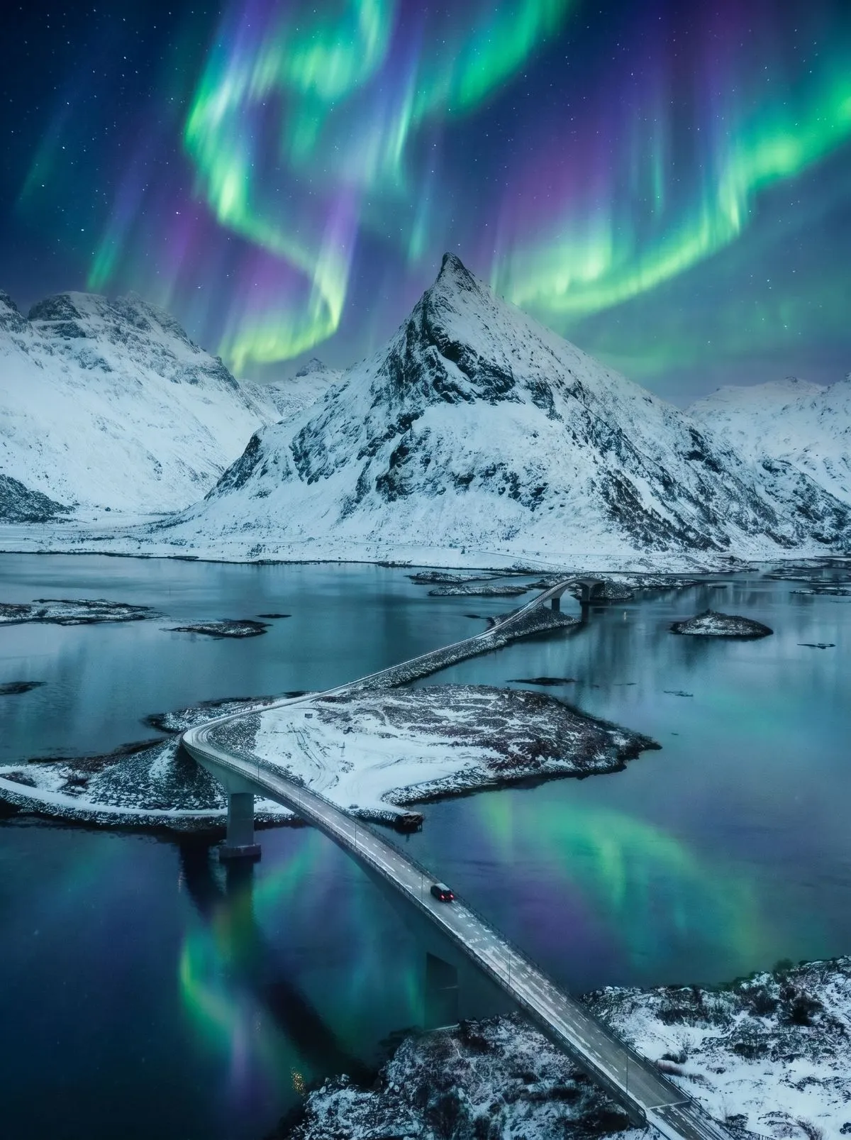 Car navigating a snowy Lofoten coastal road at night