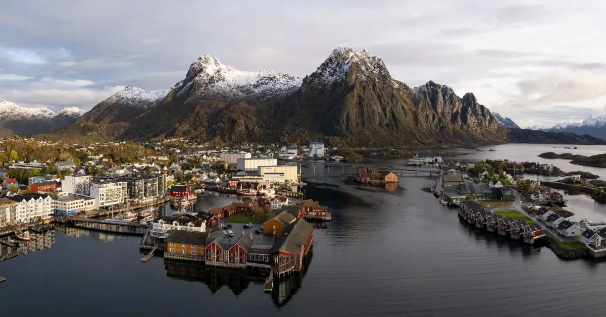 Colorful wooden fishing cabins line the calm waters of Svolvaer harbor in summer
