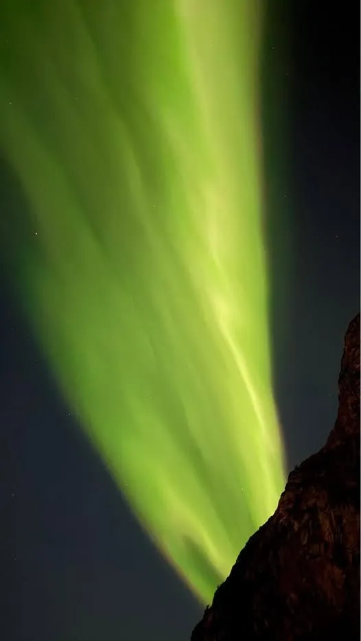 Winding Valberg road along Vestvagoy fjord beneath the northern lights