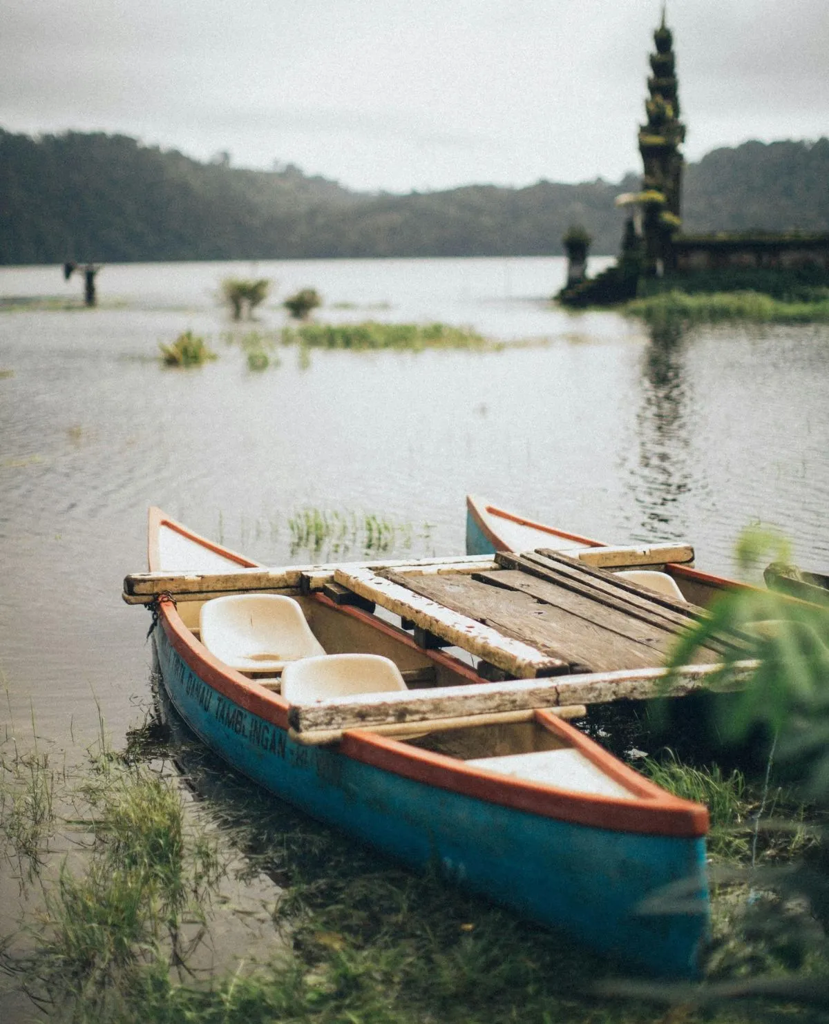 Traditional wooden dugout canoes floating on the misty waters of Lake Tamblingan in North Bali