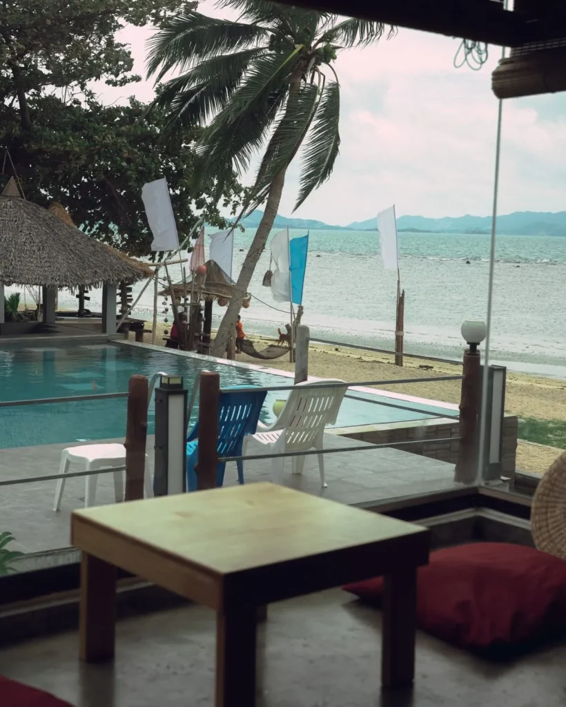 Luxury boutique beachfront resort in Ban Tai Koh Phangan featuring rustic-modern wooden architecture and a swimming pool overlooking a calm sea at sunset